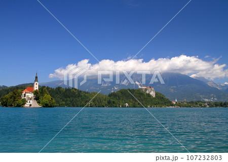 南欧スロヴェニアのブレッド湖　湖面に浮かぶブレッド島の聖母被昇天教会とブレッド城とユリアンアルプス 107232803
