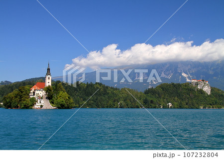 南欧スロヴェニアのブレッド湖　湖面に浮かぶブレッド島の聖母被昇天教会とブレッド城とユリアンアルプス 107232804