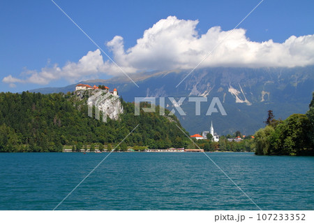 南欧スロヴェニアのブレッド湖　ターコイズブルーの湖岸の断崖の上に建つブレッド城とユリアンアルプス 107233352
