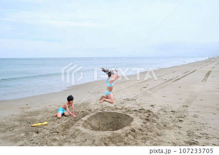 Children dig a hole in the sand on the seashore. Children dig a hole in the sand on the seashore. 107233705