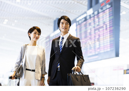 空港から出張に出かける男女の若いビジネスマン 空港から出張に出かける男女の若いビジネスマン 107236290