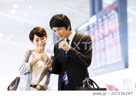 スマホを見ながら空港から出張に出かける男女の若いビジネスマン 107236297