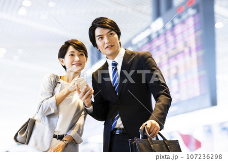スマホを見ながら空港から出張に出かける男女の若いビジネスマン 107236298