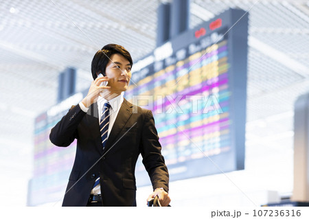 スマホで電話をする空港から出張をする若いビジネスマン 107236316