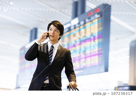 スマホで電話をする空港から出張をする若いビジネスマン 107236317