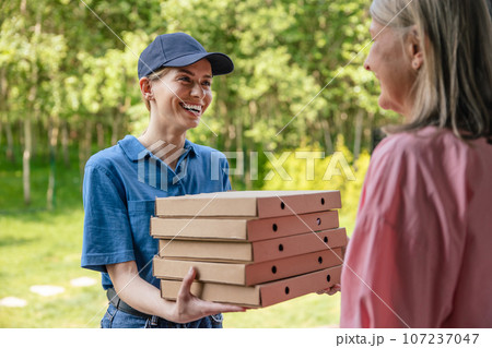 Female courier delivering pizza to client home. 107237047