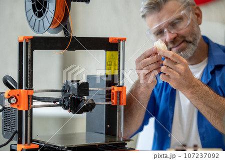 Technician printing in 3d printer, using three dimensional printing machine for work. Technician printing in 3d printer, using three dimensional printing machine for work. 107237092