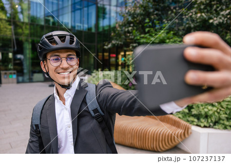 Smiling businessman in hemlet on a scooter making selfie Smiling businessman in hemlet on a scooter making selfie 107237137