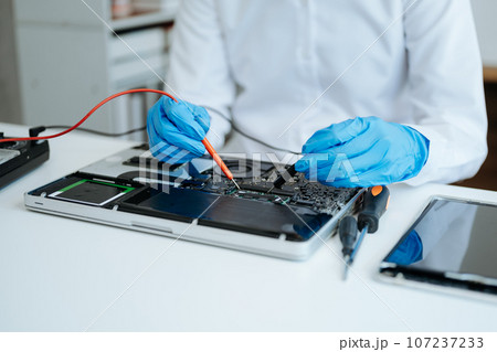 Electronics technician, electronic engineering electronic repair,electronics measuring and testing, repair and maintenance concepts.uses a voltage meter to check and upgrade 107237233