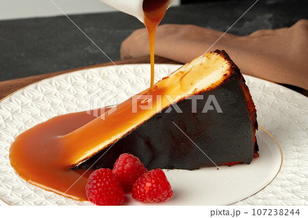 Piece of cheesecake with pouring caramel sauce on plate Piece of cheesecake with pouring caramel sauce on plate 107238244