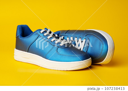 Blue new sneakers on yellow studio background Blue new sneakers on yellow studio background 107238413