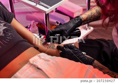 Professional tattoo artist applying antibacterial foam on tattooed skin 107238427