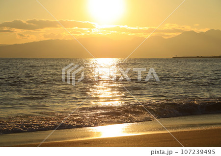 海に沈む夕日と砂浜 107239495