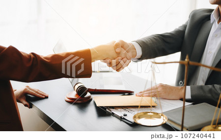 Man lawyer hand and women client shaking hand collaborate on working agreements with contract documents at the modern office. 107240441