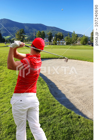 Man playing golf during a tournament against bunker Man playing golf during a tournament against bunker 107240690
