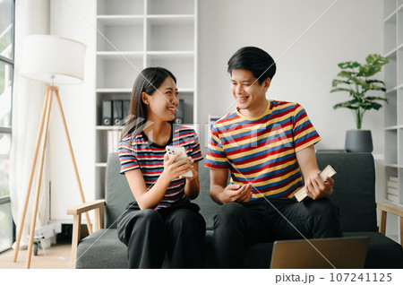 Two asian students learning together online with a laptop, tablet and tutor together in living room . 107241125