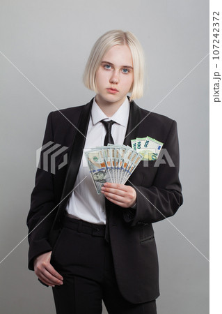 Attractive serious successful businesswoman holding money cash US Dollar and Euro banknote.  107242372