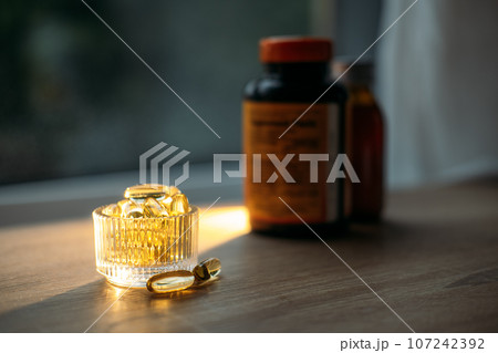 Benefits of Omega-3 for Cold Winter Months. Omega-3 fish oil Yellow Soft capsules in glass bottle on table at home. Take care of your health with fish oil 107242392