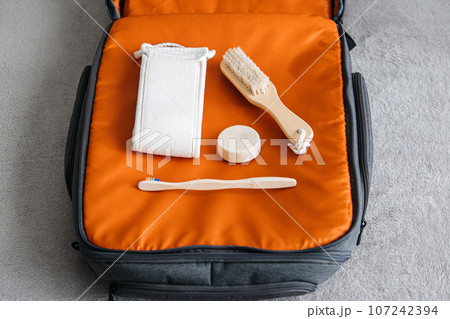 Plastic free travel, traveling sustainably. How to use less plastic on holiday. Eco Friendly Travel Products in orange suitcase. Plastic free travel, traveling sustainably. How to use less plastic on holiday. Eco Friendly Travel Products in orange suitcase. 107242394