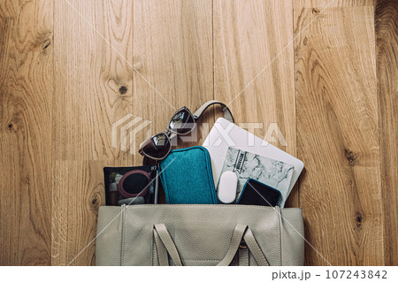 Travel Essentials Pack For Trip, Things Pack In Carry-On. Packing list for Airplane Tote. Female Carry-On luggage tote bag with laptop, notepad, glasses, headphones, cosmetics Travel Essentials Pack For Trip, Things Pack In Carry-On. Packing list for Airplane Tote. Female Carry-On luggage tote bag with laptop, notepad, glasses, headphones, cosmetics 107243842