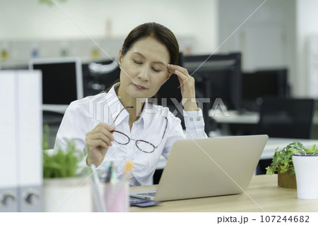 オフィスでこめかみを抑えるミドルエイジの女性 107244682