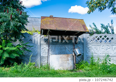 Old well with iron bucket on long forged chain for clean drinking water 107246742