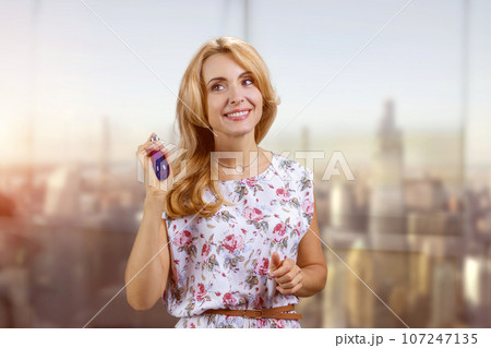 Happy blonde woman holding perfume bottle applying it on hers neck. New luxury fragrance concept. Happy blonde woman holding perfume bottle applying it on hers neck. New luxury fragrance concept. 107247135