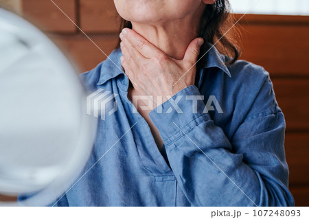 首のシワを鏡で確認するシニア女性 107248093
