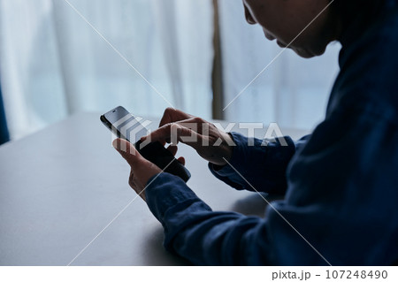 部屋でスマホを操作するシニア女性 107248490