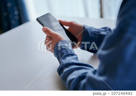 部屋でスマホを操作するシニア女性 部屋でスマホを操作するシニア女性 107248492