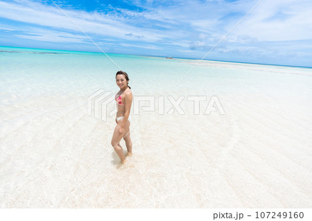 遠浅のビーチで微笑むビキニ姿の若い女性 107249160