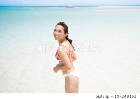 遠浅のビーチで微笑むビキニ姿の若い女性 107249163