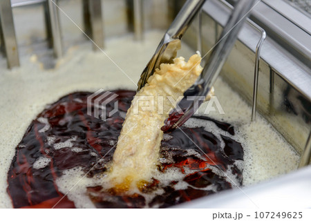 業務用フライヤーで魚を揚げる、揚げ物、魚のフライ 107249625