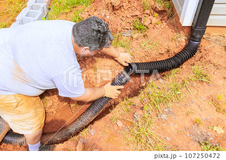 Drainage pipe connector downspout installation for flexible gutter extension with water draining down Drainage pipe connector downspout installation for flexible gutter extension with water draining down 107250472