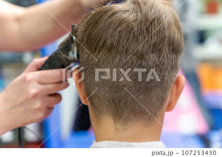 Hair cutting for a child using a hair clipper in a beauty salon 107253430