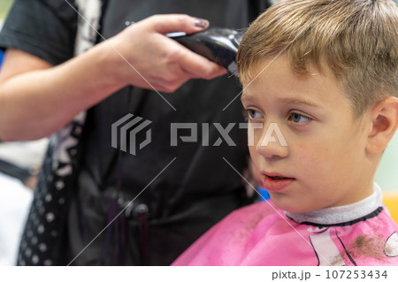 Hair cutting for a child using a hair clipper in a beauty salon Hair cutting for a child using a hair clipper in a beauty salon 107253434
