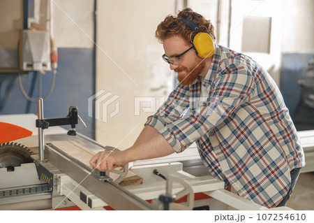 Woodworker sawing a board with a circular saw in a carpentry workshop. High quality photo 107254610