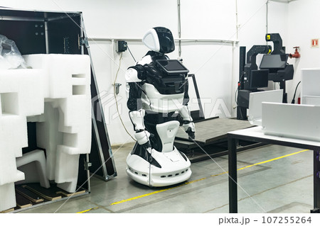 newly assembled humanoid robot in a workshop is being charged before packaging 107255264