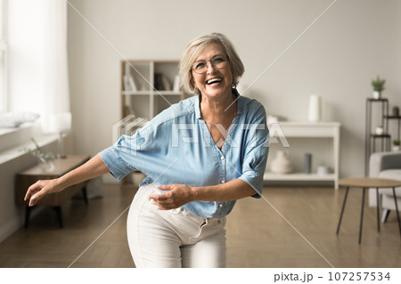 Joyful happy retired woman in glasses having fun at home 107257534