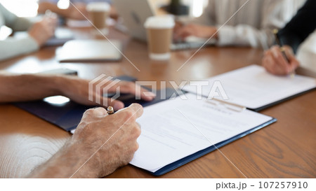 Seated at desk parties putting signature on commercial agreement closeup 107257910