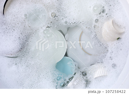 Dishes and bowls in water and bubbles of dishwashing liquid. Kitchen work Dishes and bowls in water and bubbles of dishwashing liquid. Kitchen work 107258422