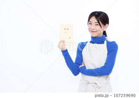 白い背景の前で給料袋を持って考えている笑顔の30代主婦 白い背景の前で給料袋を持って考えている笑顔の30代主婦 107259690