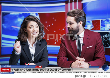News anchors announce end of long war between israel and palestine, celebrating peace treaty signed by nations fighting for decades. Man and woman journalists on talk show in newsroom. 107259850