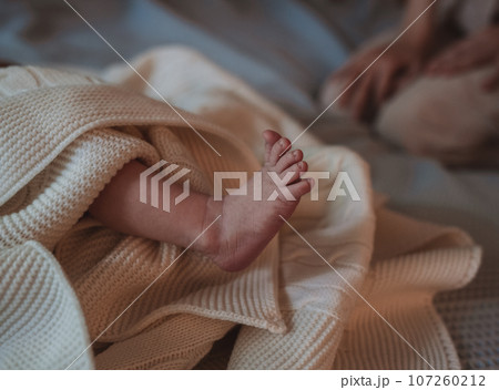 legs of a newborn baby in a beige muslin swaddle. close-up shot legs of a newborn baby in a beige muslin swaddle. close-up shot 107260212