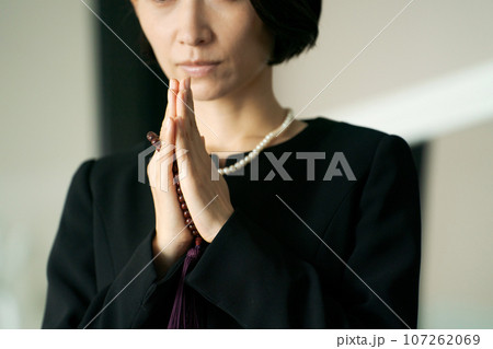 葬儀で手を合わせてお参りする女性 107262069