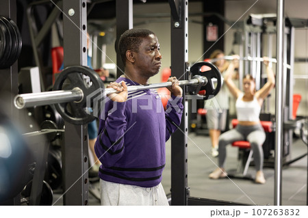 African american man doing barbell squats in gym African american man doing barbell squats in gym 107263832