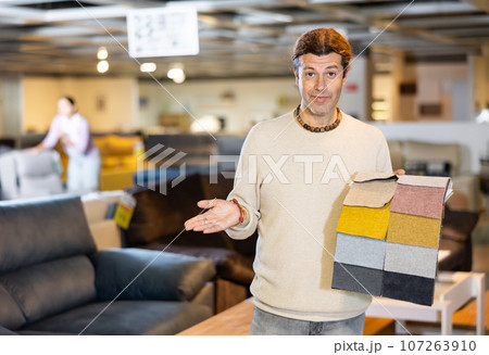 Middle-aged man shows upholstery fabric 107263910