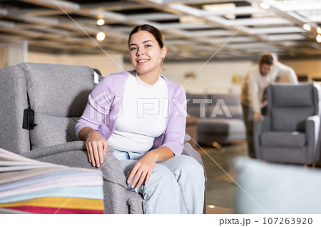 Female furniture salesperson showing armchairs for sale in furniture showroom Female furniture salesperson showing armchairs for sale in furniture showroom 107263920
