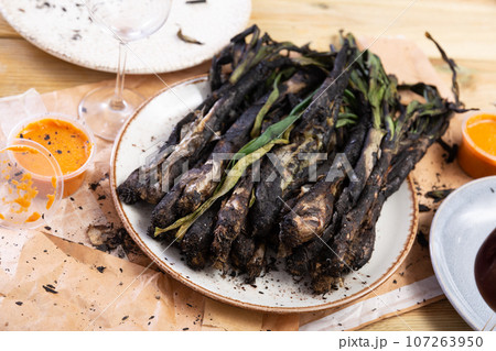 On round plate - fried sweet green onions kalsot, supplemented with jar of romesco sauce,red wine 107263950