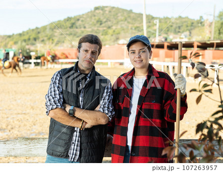 Portrait of a married couple owners of stable against the backdrop of corral for walking horses Portrait of a married couple owners of stable against the backdrop of corral for walking horses 107263957